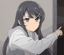 a girl with long black hair and blue eyes is pointing