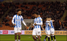 a group of soccer players are hugging each other on a field with a sky bet banner in the background