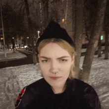 a woman wearing a black hat and a black jacket is standing in the snow