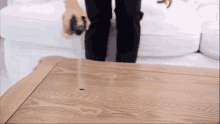 a person is standing on a wooden table with a remote control in their hand .