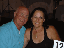 a man and a woman are posing for a picture with a table number 12 in the foreground