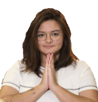 a woman with glasses and a tattoo on her arm is praying with her hands together