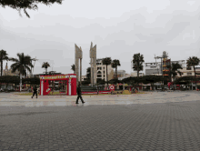 a man walks in front of a red kiosk that says ' alianza ' on it