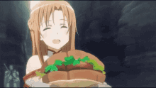 a girl is holding a hamburger with lettuce and tomatoes in her hand .