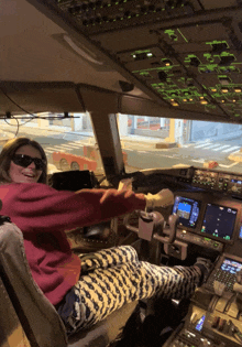 a woman wearing sunglasses is sitting in the cockpit of a plane