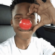 a young man is wearing a red clown nose with a tear running down his eye .