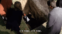 a man in a suit and tie is laying in the dirt and says i 'm fine