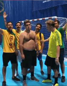 a group of men are standing in front of a soccer goal and one of them is wearing a shirt that says ' brasil '