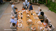 a group of people are gathered around a long table with plates of food on it and a nbc logo in the corner