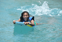 a woman is smiling while riding a boogie board in the ocean