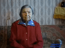 an elderly woman is sitting on a couch in front of a microphone .