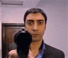 a man in a suit is holding a gun in front of his face and pointing it at the camera .