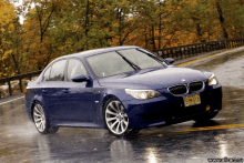 a blue car with a new york license plate is driving on a wet road