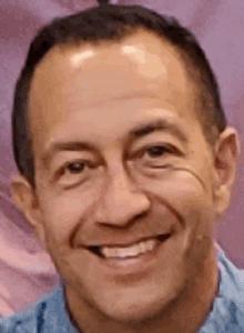 a close up of a man 's face with a purple background smiling .