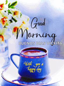 a blue cup of coffee sits on a saucer with the words " good morning buenos dias vikita " written above it