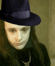 a man with long hair is wearing a purple fedora hat