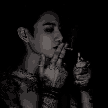 a tattooed man is smoking a cigarette with the word love on his hand