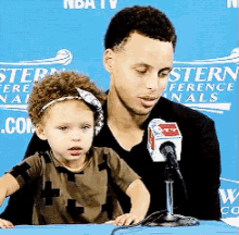 a man and a child are sitting in front of a microphone in front of a blue background that says stern conference finals