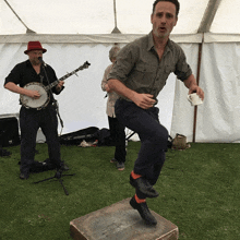 a man in a hat is playing a banjo while another man is singing into a microphone