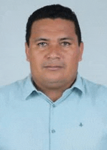 a man in a light blue shirt is standing in front of a white background .