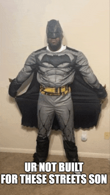 a man in a batman costume is standing in front of a wall