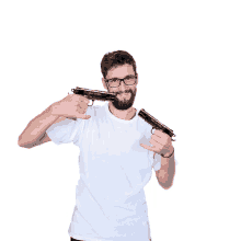 a man with glasses and a beard holds two guns in front of his face