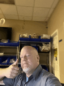 a man giving a thumbs up in front of a shelf with blue bins on it