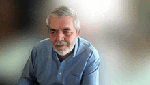 a man with gray hair and a beard is wearing a light blue shirt