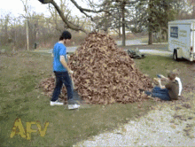 a pile of leaves is being raked by a man and a woman with the letters afv in the corner