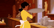 a woman in a yellow apron is holding a tray in a kitchen