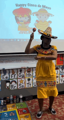 a woman in a yellow dress and sombrero is holding a maraca