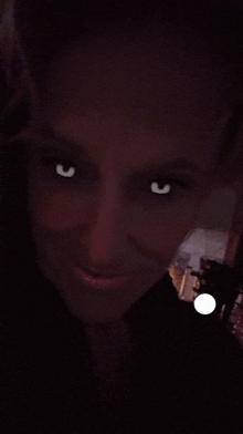 a close up of a woman 's face with glowing eyes in the dark