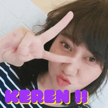 a girl is making a peace sign with her fingers and the word keren is on the bottom