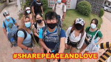 a group of people wearing face masks are standing in front of a sign that says share peace and love