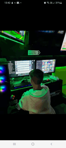 a young boy is playing a video game on a computer in a room with a sign that says " streamer zone " on the wall