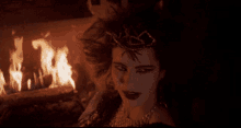 a woman with a crown on her head is in front of a fire