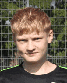 a young man with red hair is wearing a black shirt with green stripes on the sleeves .