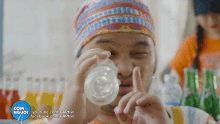 a man in a colorful hat is holding a glass of water in front of a facebook logo that says com người