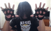 a person wearing a kegel t-shirt holds up their hands