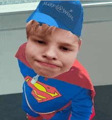 a boy in a superman costume with a make a wish hat on