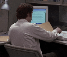 a man sits at a desk in front of a computer with the letter a on the wall behind him