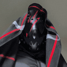 a person wearing a black and red helmet is wrapped in a black blanket