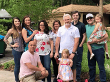 a group of people posing for a picture including a little girl wearing a pink dress