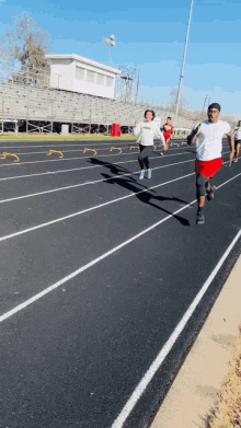 a group of people are running on a track and one of them is wearing a white shirt that says adidas