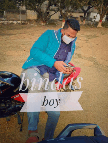 a man wearing a face mask is sitting on a motorcycle with the words bindas boy written below him