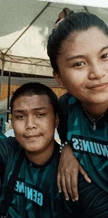 a man and a woman are posing for a picture and the woman is wearing a shirt that says ' cemile '