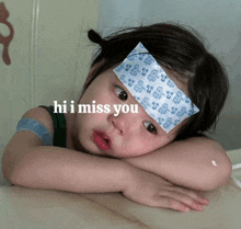 a little girl with a bandage on her forehead and the words hi i miss you above her