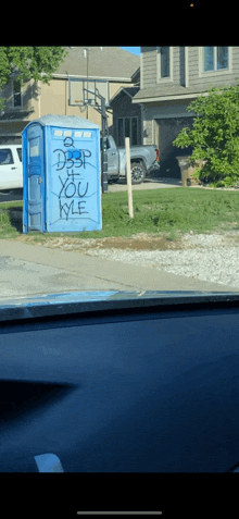 a blue portable toilet has graffiti on it that says " do n't dust you kyle "