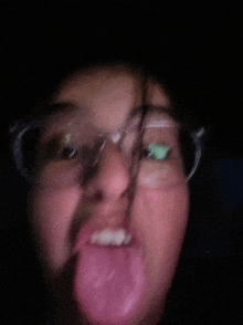 a woman wearing glasses sticks out her tongue