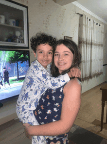 a girl is holding a boy in her arms in front of a television